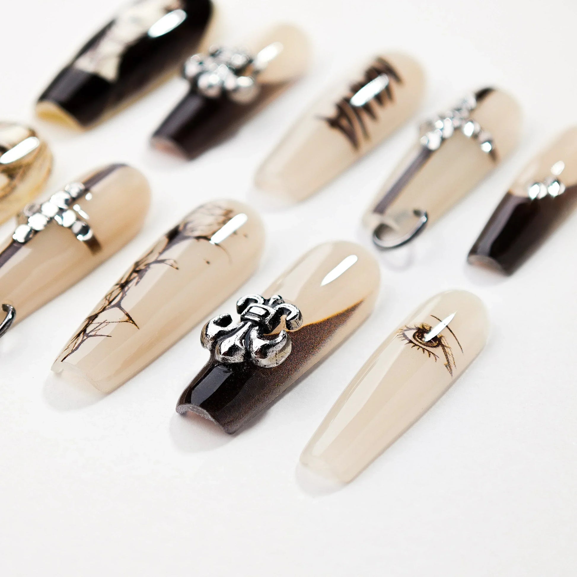 Set of black and beige stylish artificial nails with eye and metallic embellishment designs